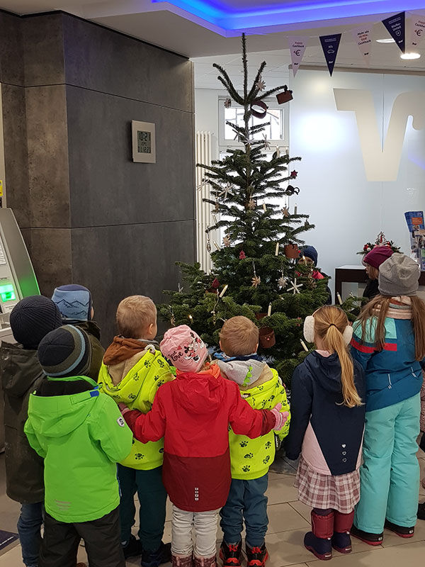 Kinder singen Weihnachtslieder neben dem Weihnachtsbaum