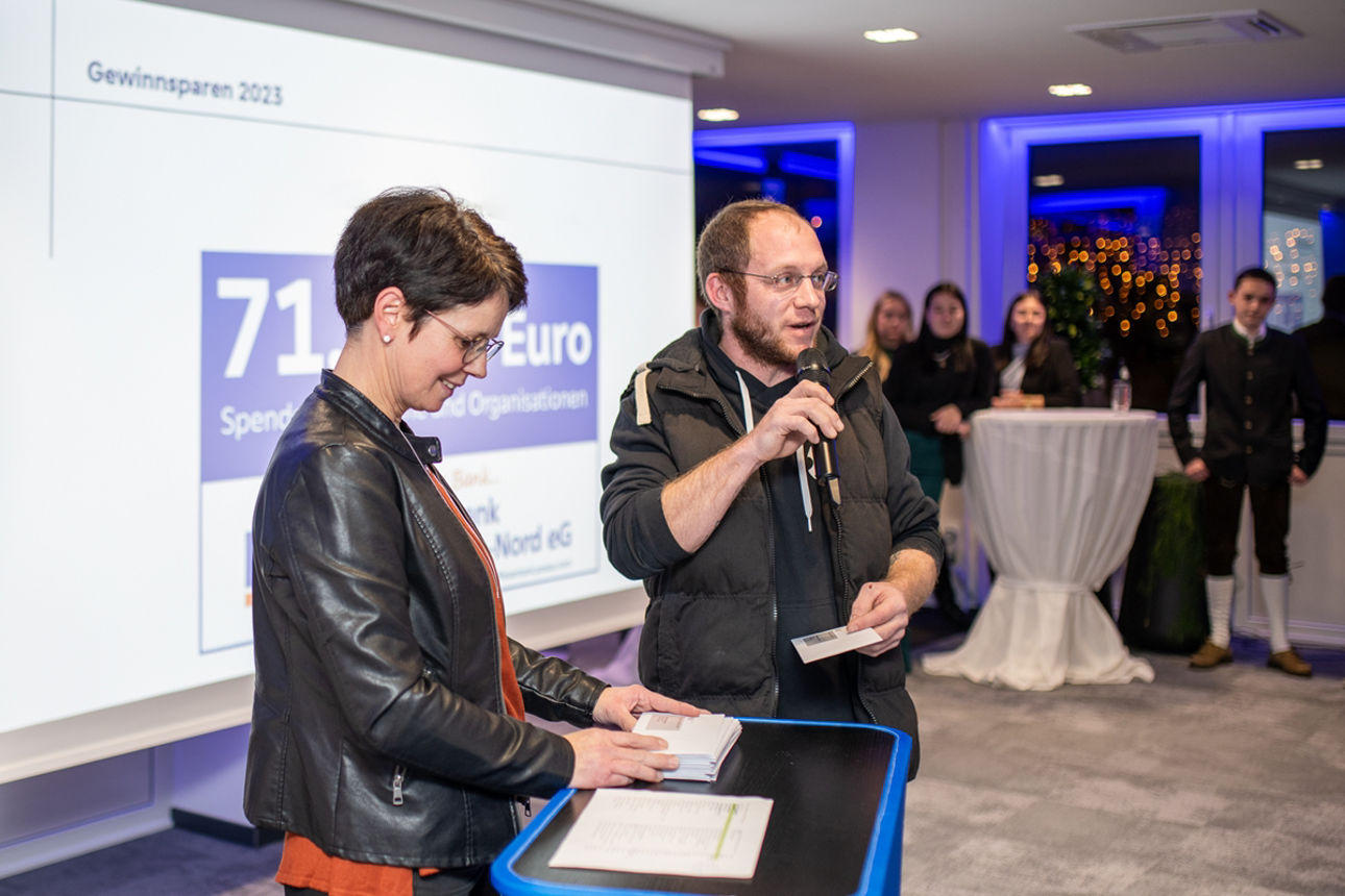 Mann mit Mikrofon und Frau an Rednepult