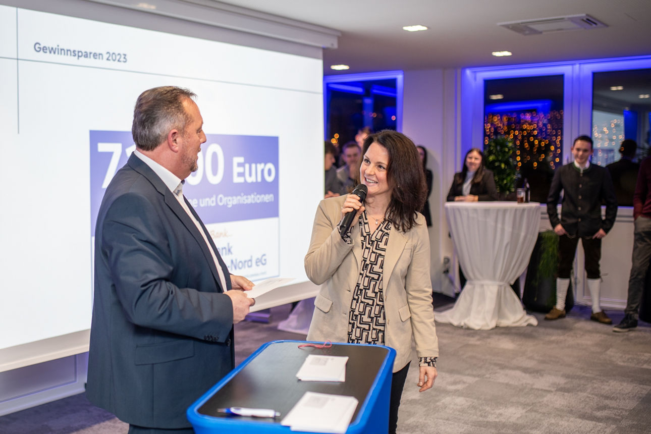 Mann und Frau stehen vor Leinwand mit Mikrofon