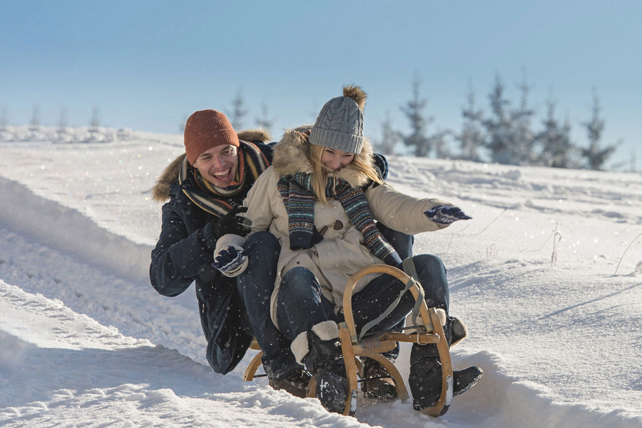 Paar sitzt auf einem Schlitten in einer Schneelandschaft