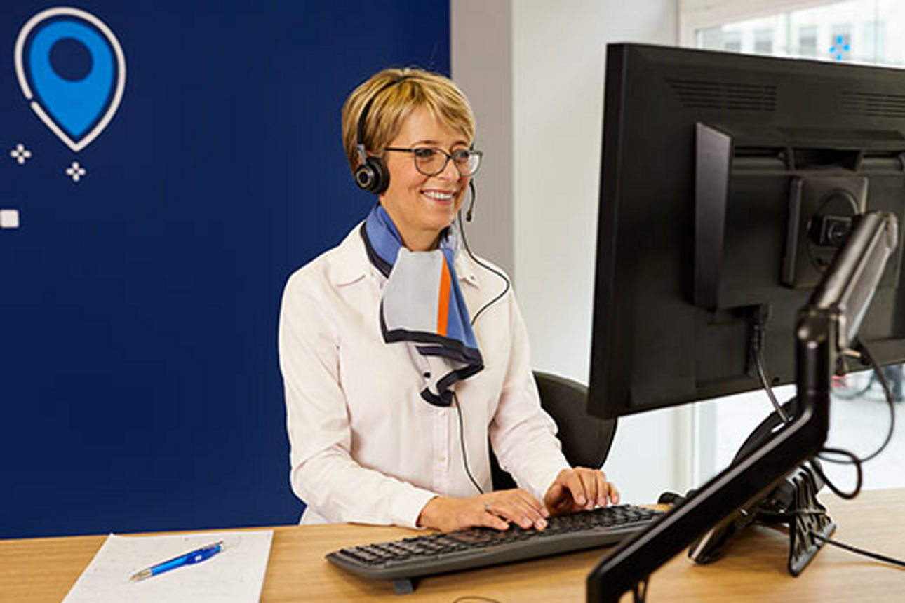 Beraterin mit Headset vor einem Computer in einer Bankfiliale