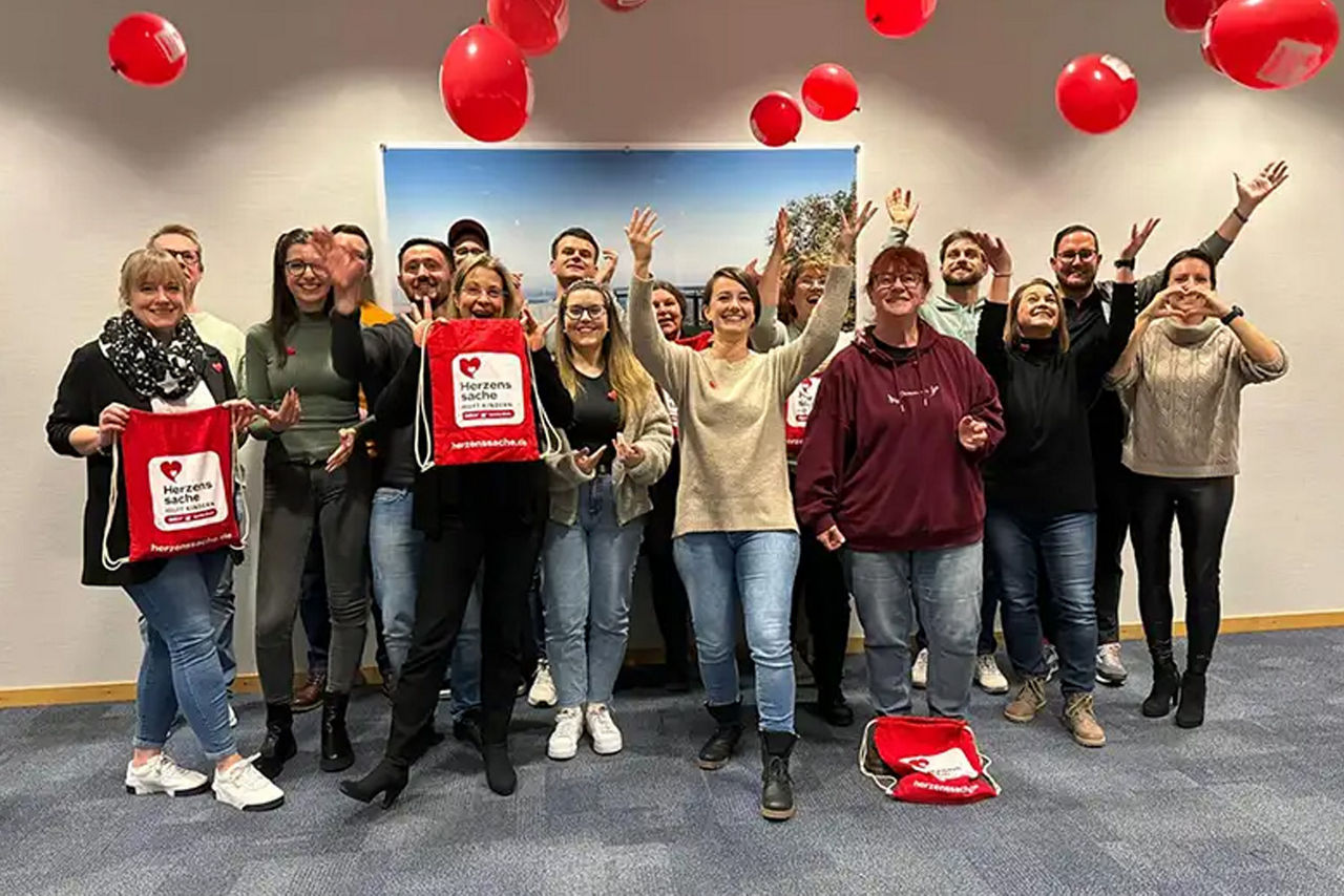 Mitarbeiter feiern mit roten Luftballons