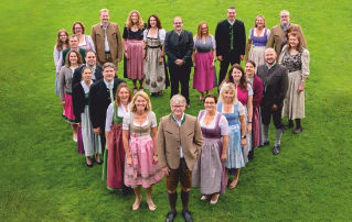 Mitarbeiter stehen in Herzform auf der Wiese