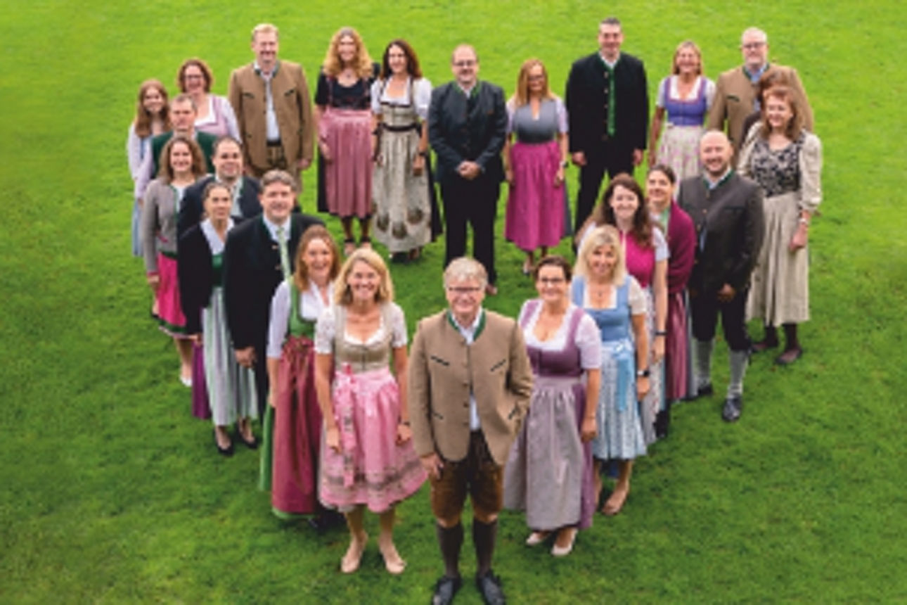 Mitarbeiter stehen in Herzform auf der Wiese