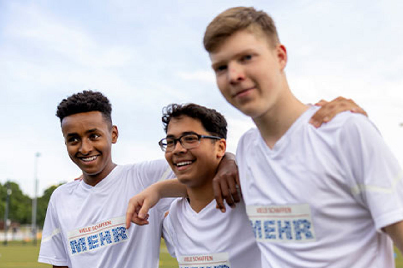 Drei junge Fußballspieler mit dem „Viele schaffen mehr“-Logo auf den Trikots