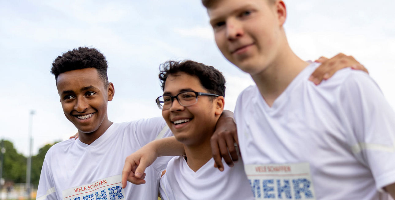 Drei junge Fußballspieler mit dem „Viele schaffen mehr“-Logo auf den Trikots