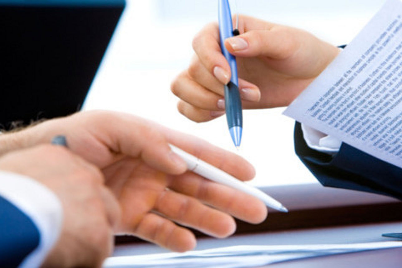 Hände mit Unterlagen zur Vertragsunterzeichnung