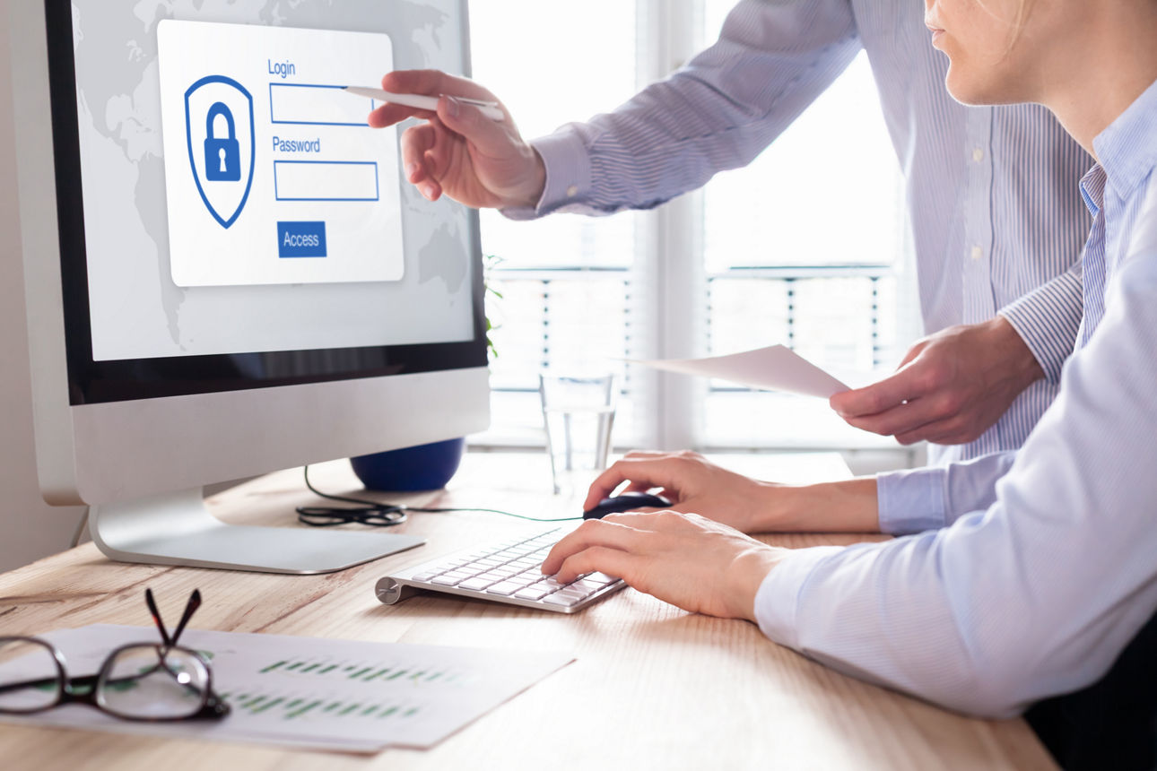 Cyber-Resilienz: Was das NIS‑2-Gesetz für Unternehmen bedeutet Personen geben Login-Daten am Computer ein, während jemand auf den Bildschirm zeigt.