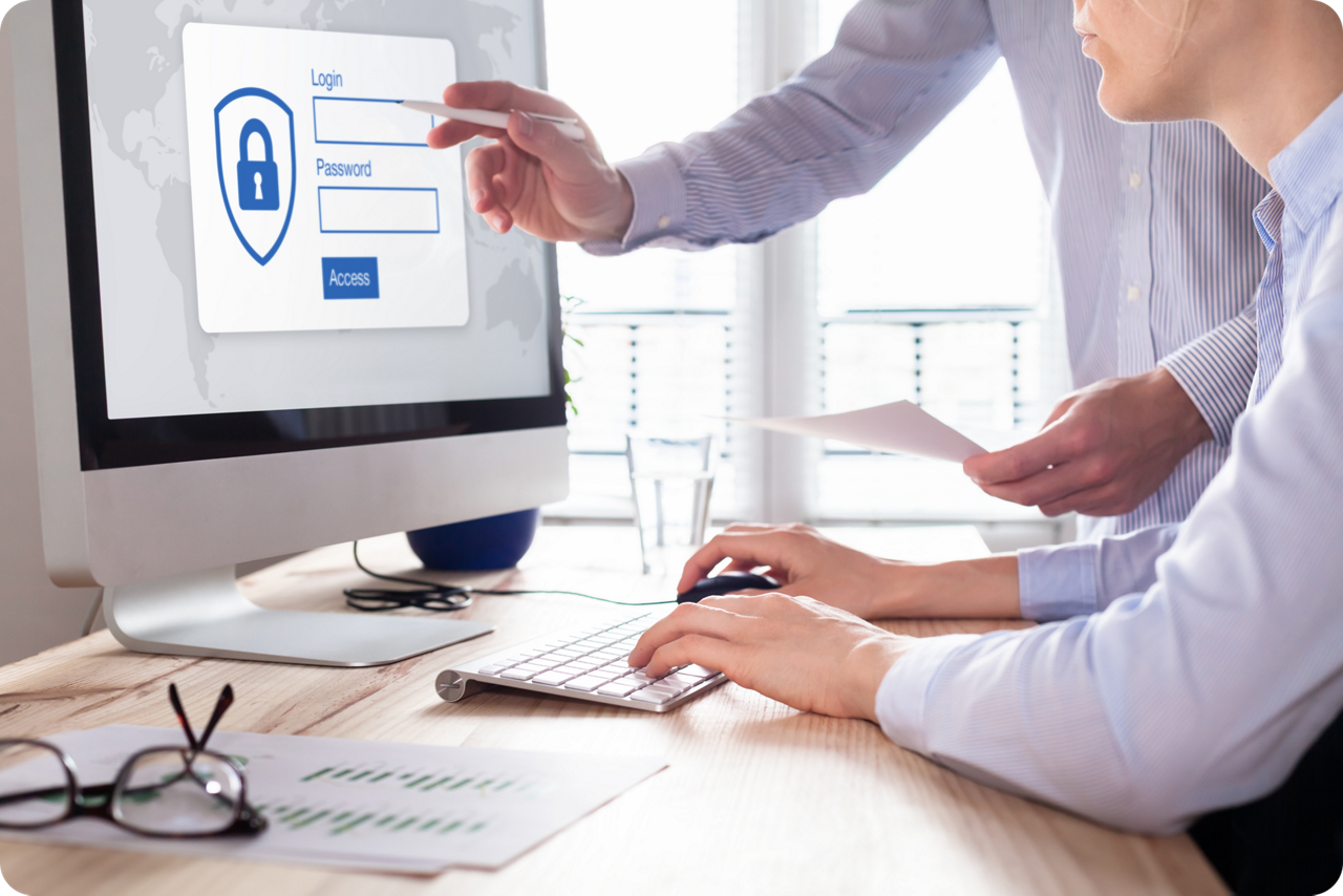 Personen geben Login-Daten am Computer ein, während jemand auf den Bildschirm zeigt.