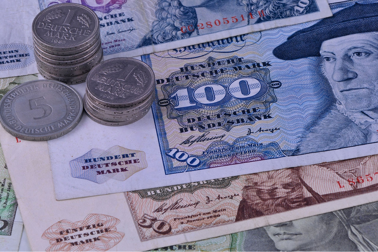 Verschieden D-Mark-Scheine liegen übereinander. Darauf zwei Stapel Ein-D-Mark Münzen und eine Fünf-D-Mark Münze