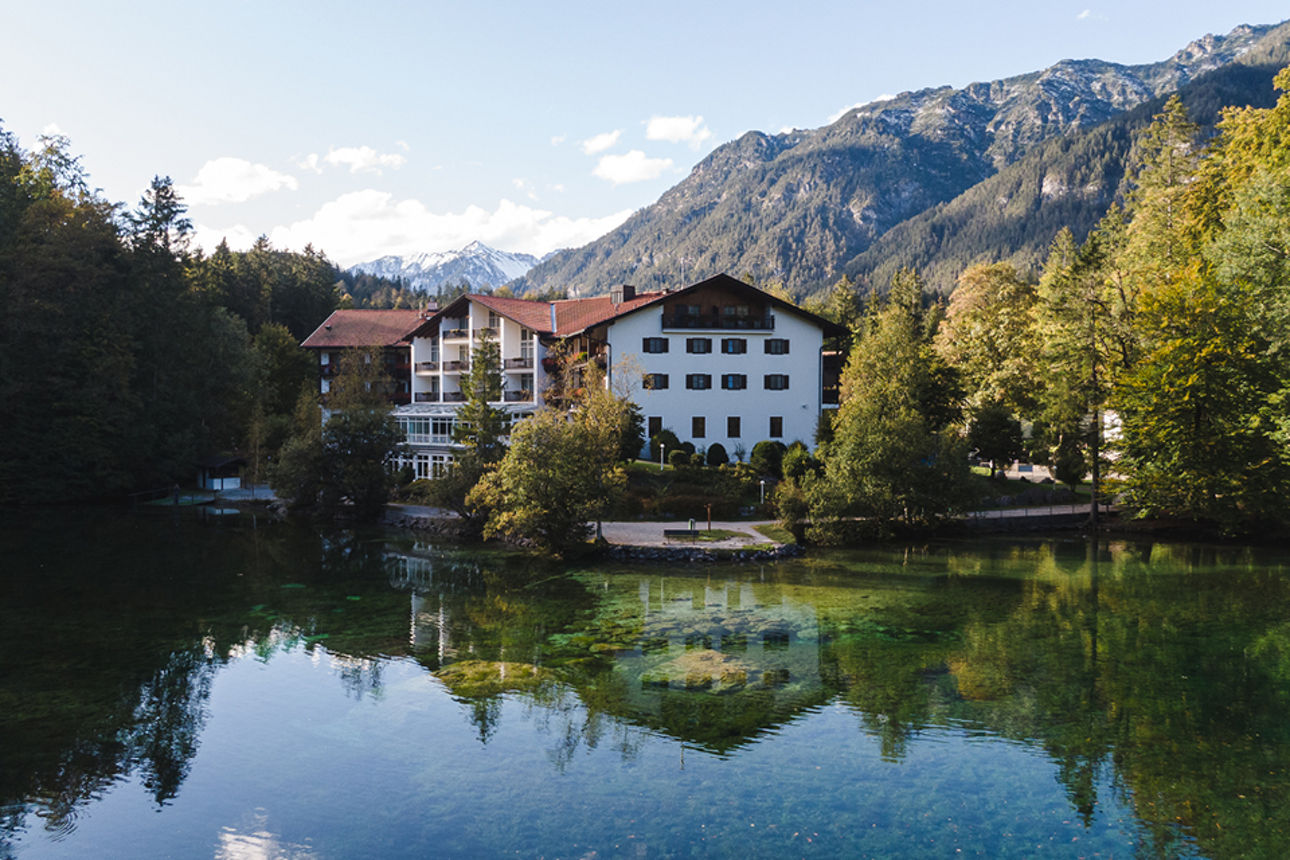 Holzsteg am See mit glitzerndem Sonnenlicht und Bergpanorama im Hintergrund