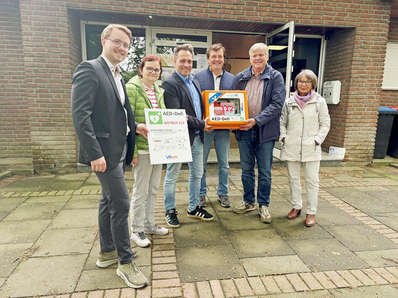 Aufsichtsratsmitglied Dirk Hasselkamp überreicht einen Defi für das Dorfgemeinschaftshaus Oberlohberg