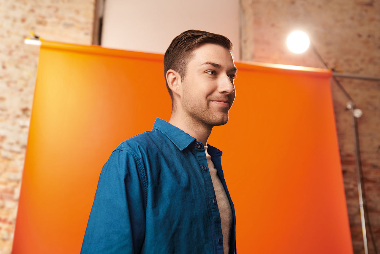 Junger Mann vor einer orangenen Wand