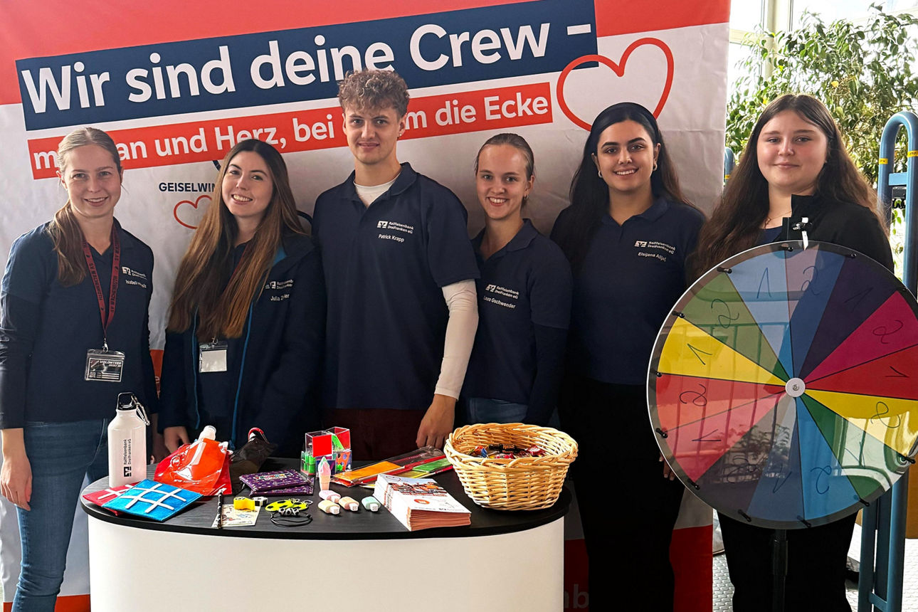Teammitglieder des Jugendmarkts der Bank stehen an ihrem Messestand.