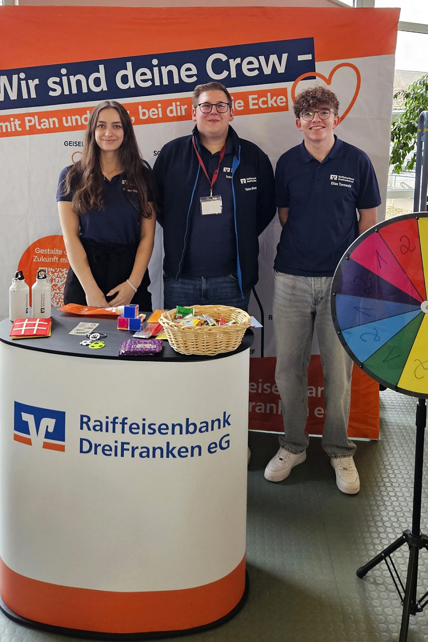 Teammitglieder des Jugendmarkts der Bank stehen an ihrem Messestand.