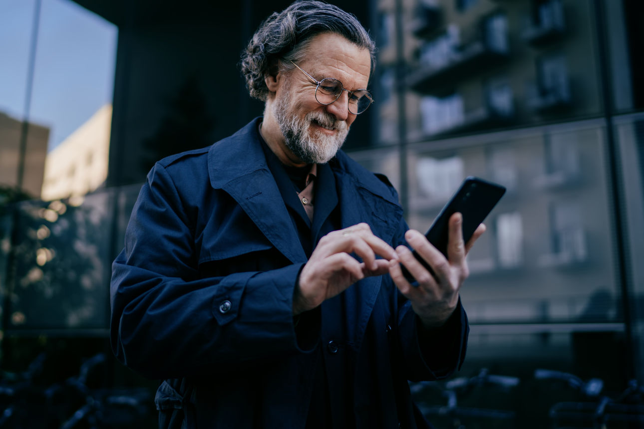 Eine Person liegt auf einem Sofa und bedient mit einem Smartphone eine digitale Anwendung in einem Wohnraum