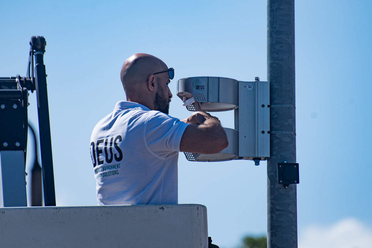 Techniker installiert ein Umweltmessgerät an einem Mast mithilfe einer Hubarbeitsbühne unter freiem Himmel