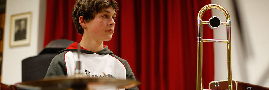 Junge im bei der Chorprobe vor einem Instrument stehend