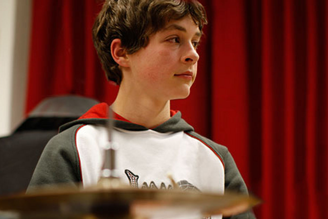 Junge im bei der Chorprobe vor einem Instrument stehend