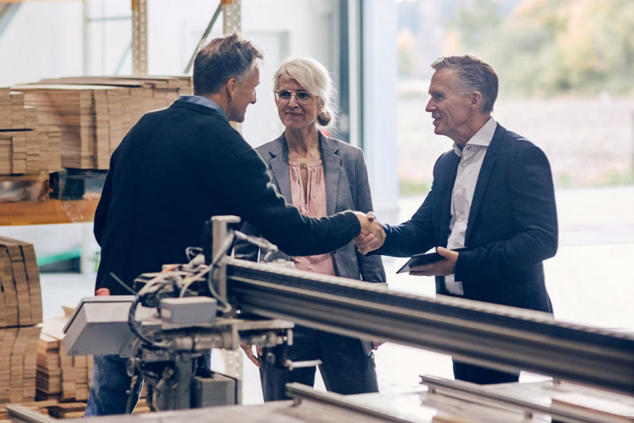 Ansprechpartner mit Händeschlag gegenüber glücklichen Kunden