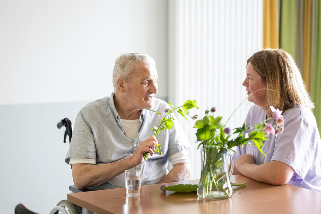 Pflegerin und Senior riechen an verschiedenen Kräutern