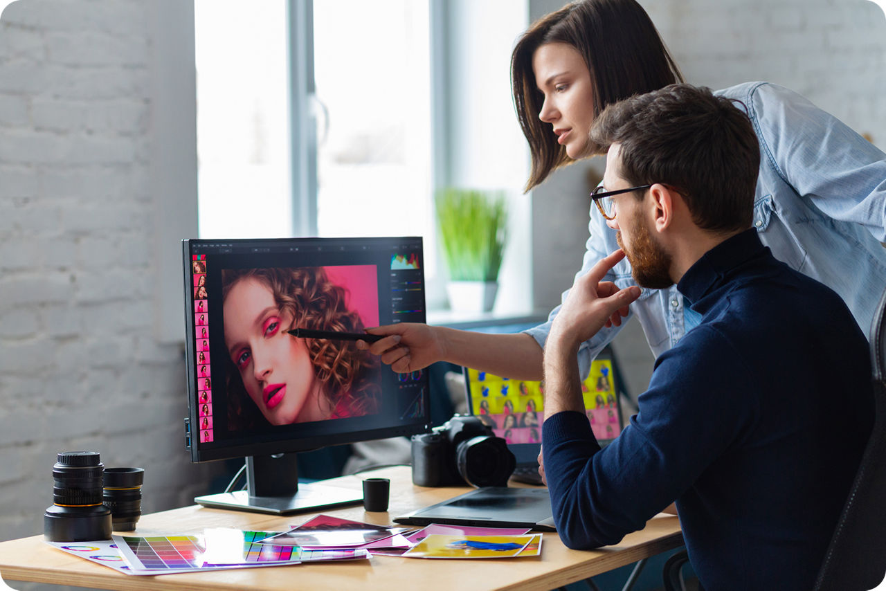 Ein Mann und einen Frau stehen vor einem Computer und arbeiten