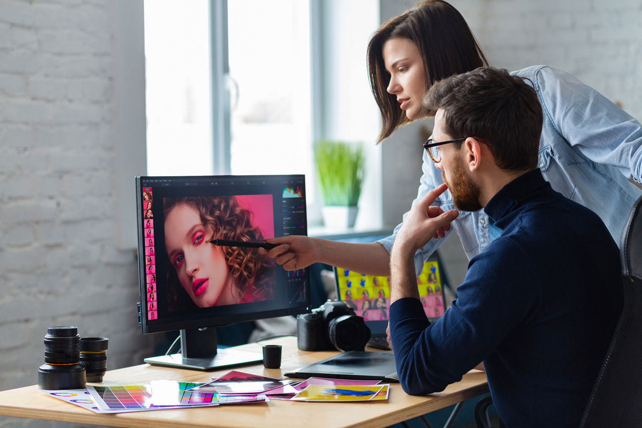 Ein Mann und einen Frau stehen vor einem Computer und arbeiten