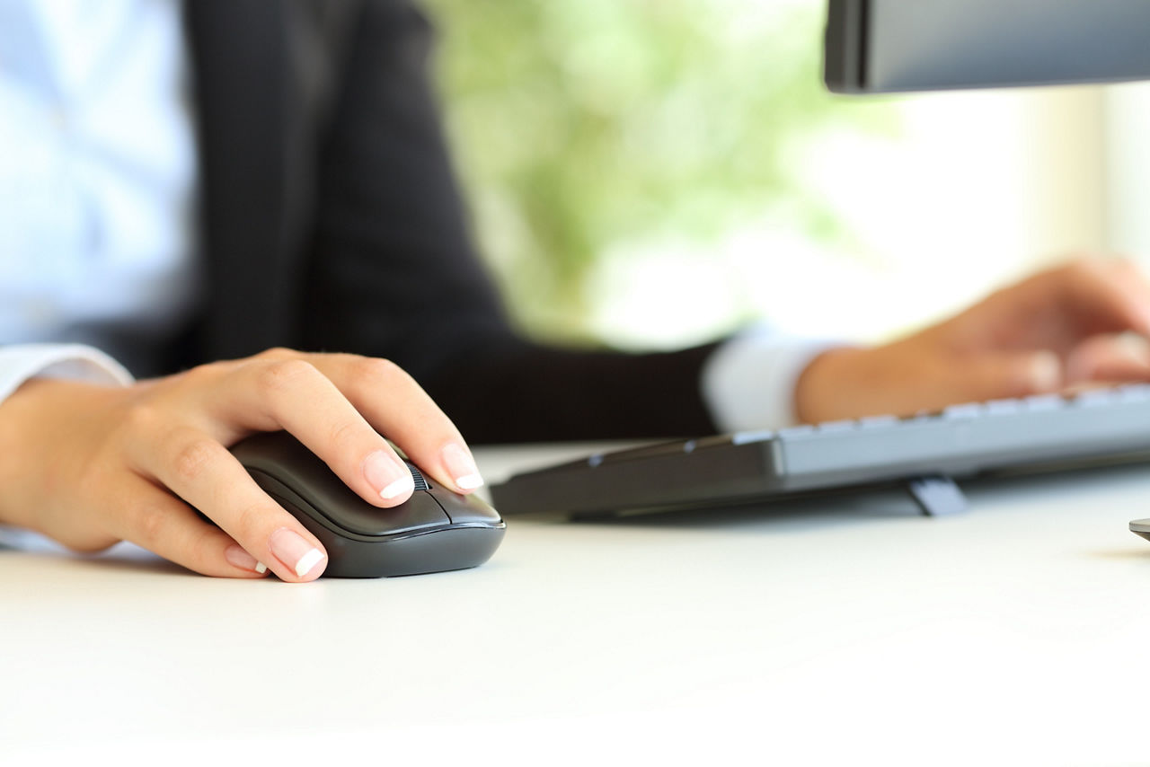 Junger Mann sitzt in der Küche vor seinem Laptop und macht Home Office, er legt sich entspannt zurück weil er seine Finanzen im Griff hat