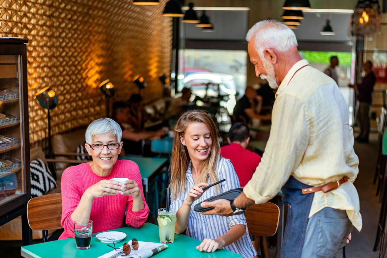  Mutter und Tochter bezahlen im Restaurant bequem per Smartphone