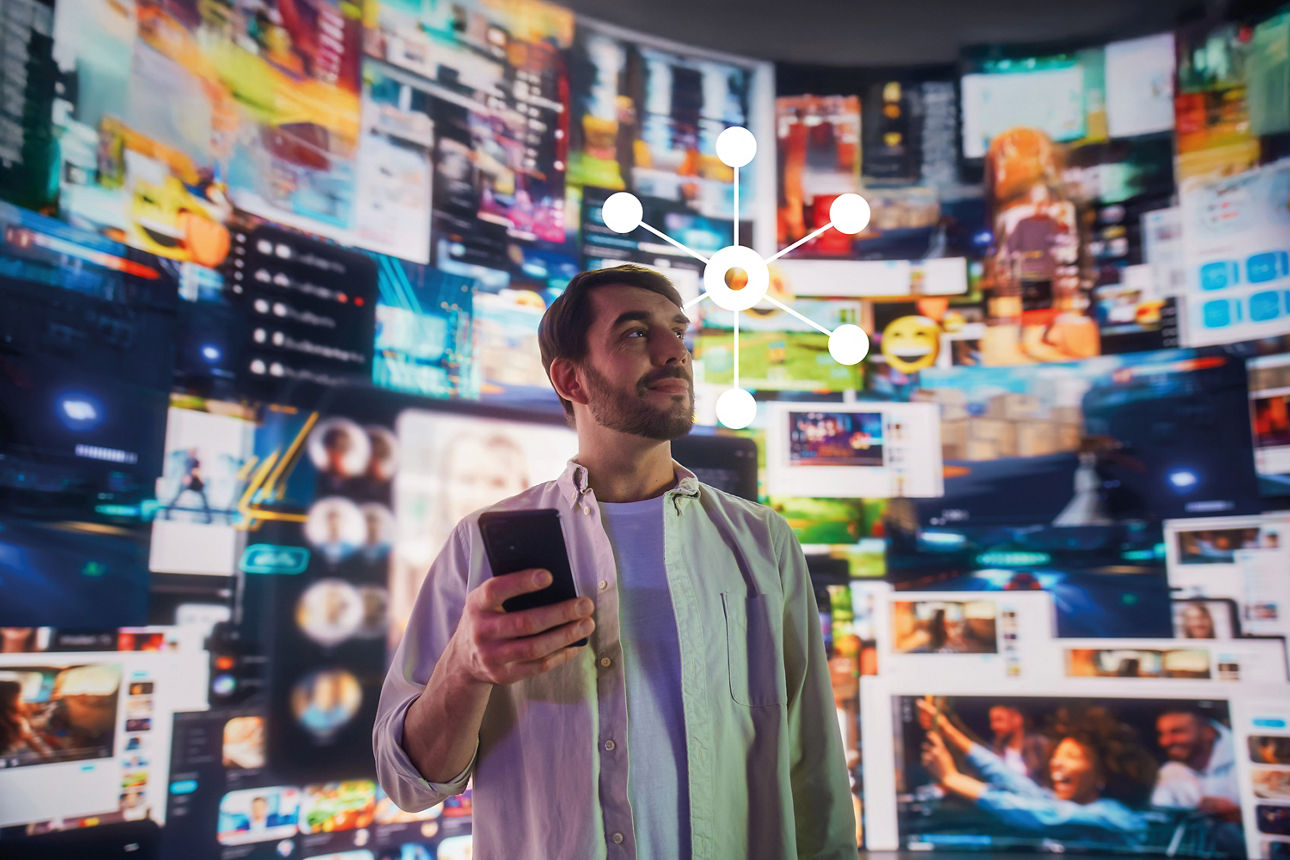 Ein junger Mann mit einem Handy in der Hand, während im Hintergrund die digitale Welt zu sehen ist.