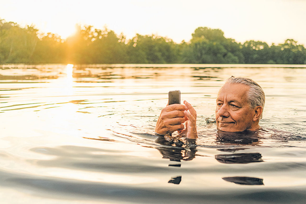 Älterer Mann in einem See mit seinem Handy