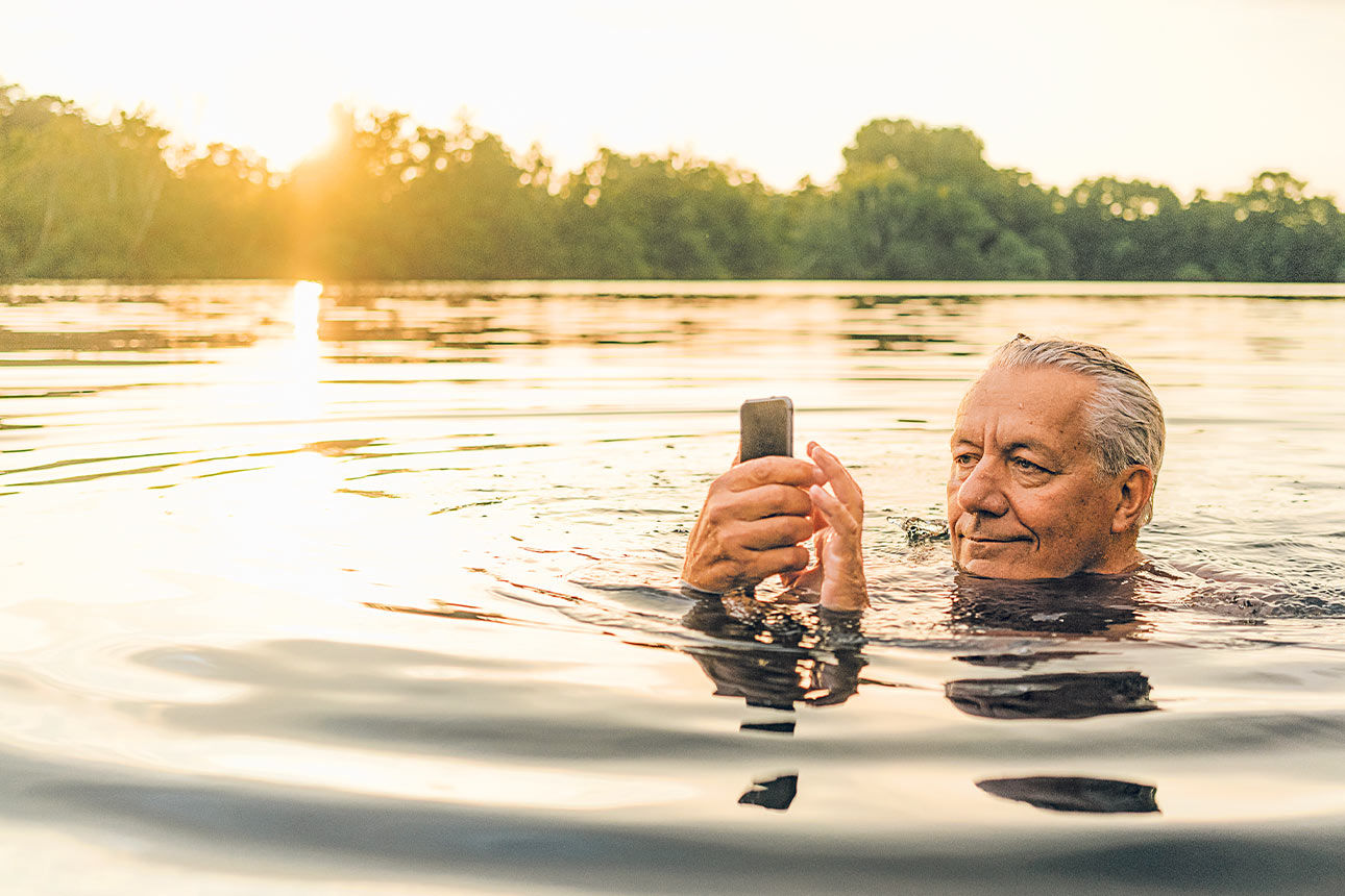Mann im See der sein Handy nutzt 