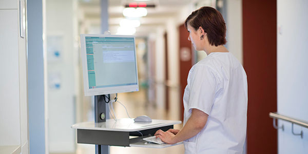 Krankenschwester arbeitet auf dem Krankenhausflur am mobilen Rechner.