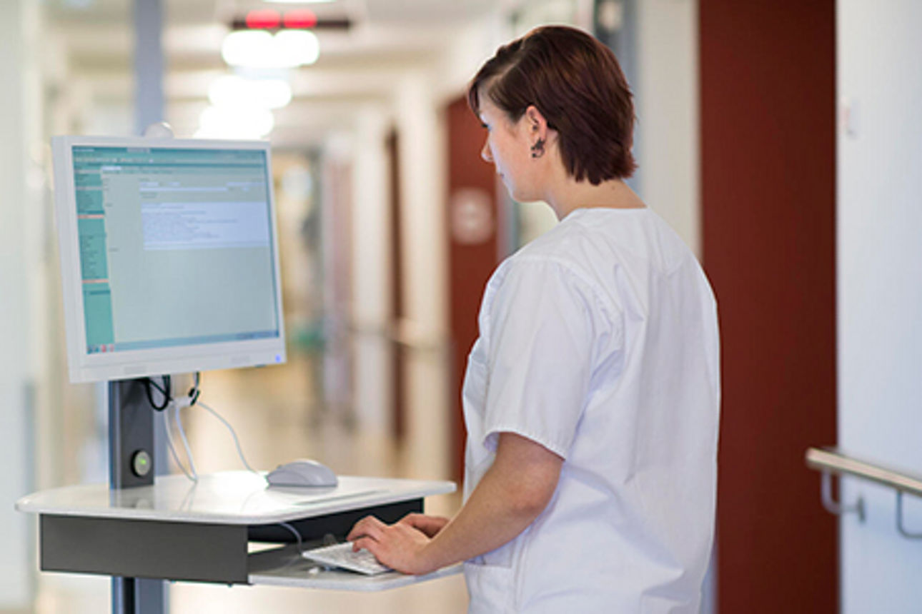 Krankenschwester arbeitet auf dem Krankenhausflur am mobilen Rechner.