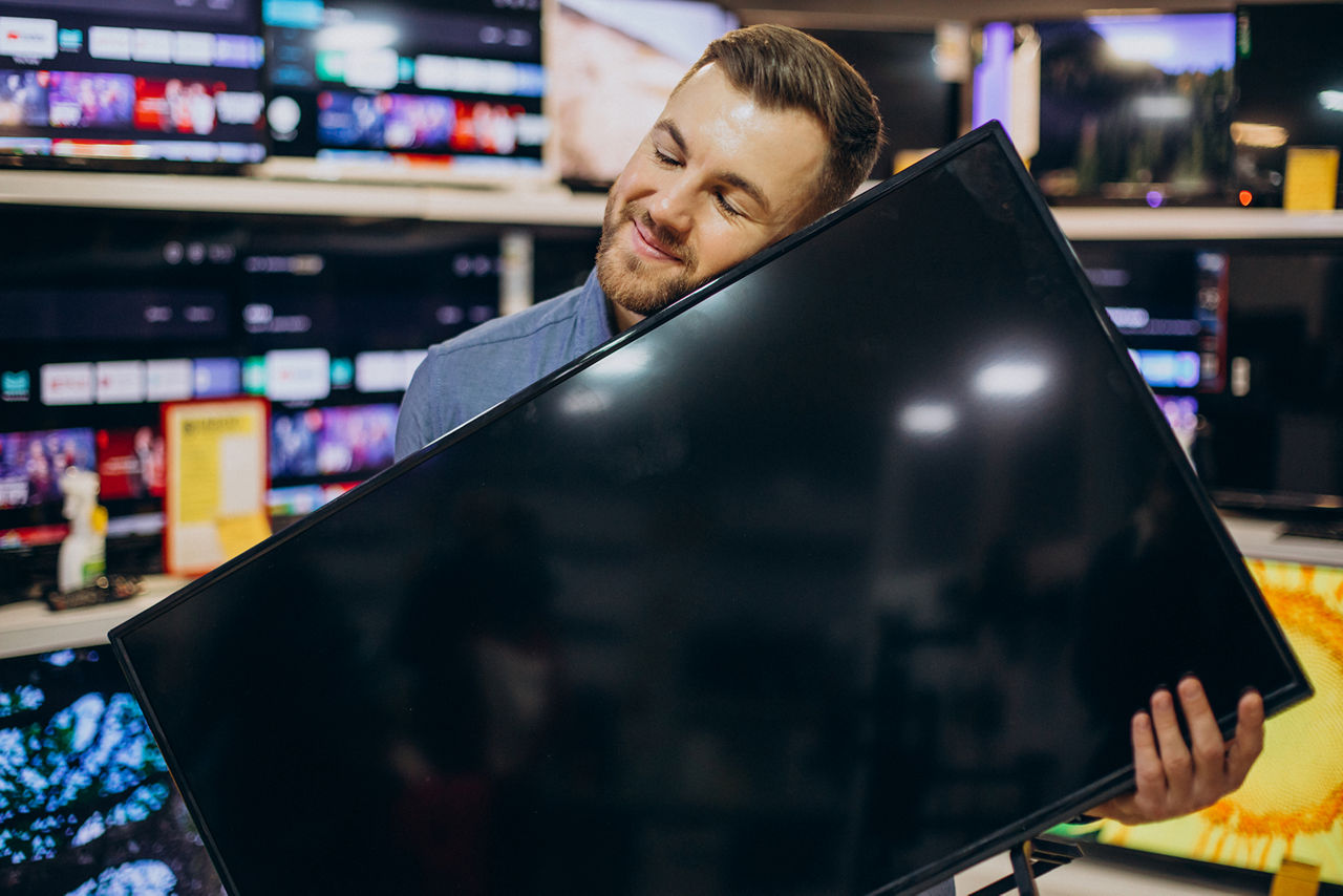 Mann hält glücklich seinen neuen Fernseher in der Hand