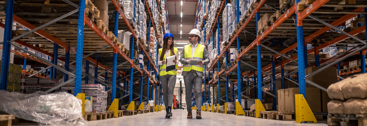 Zwei Logistiker laufen durch eine Lagerhalle