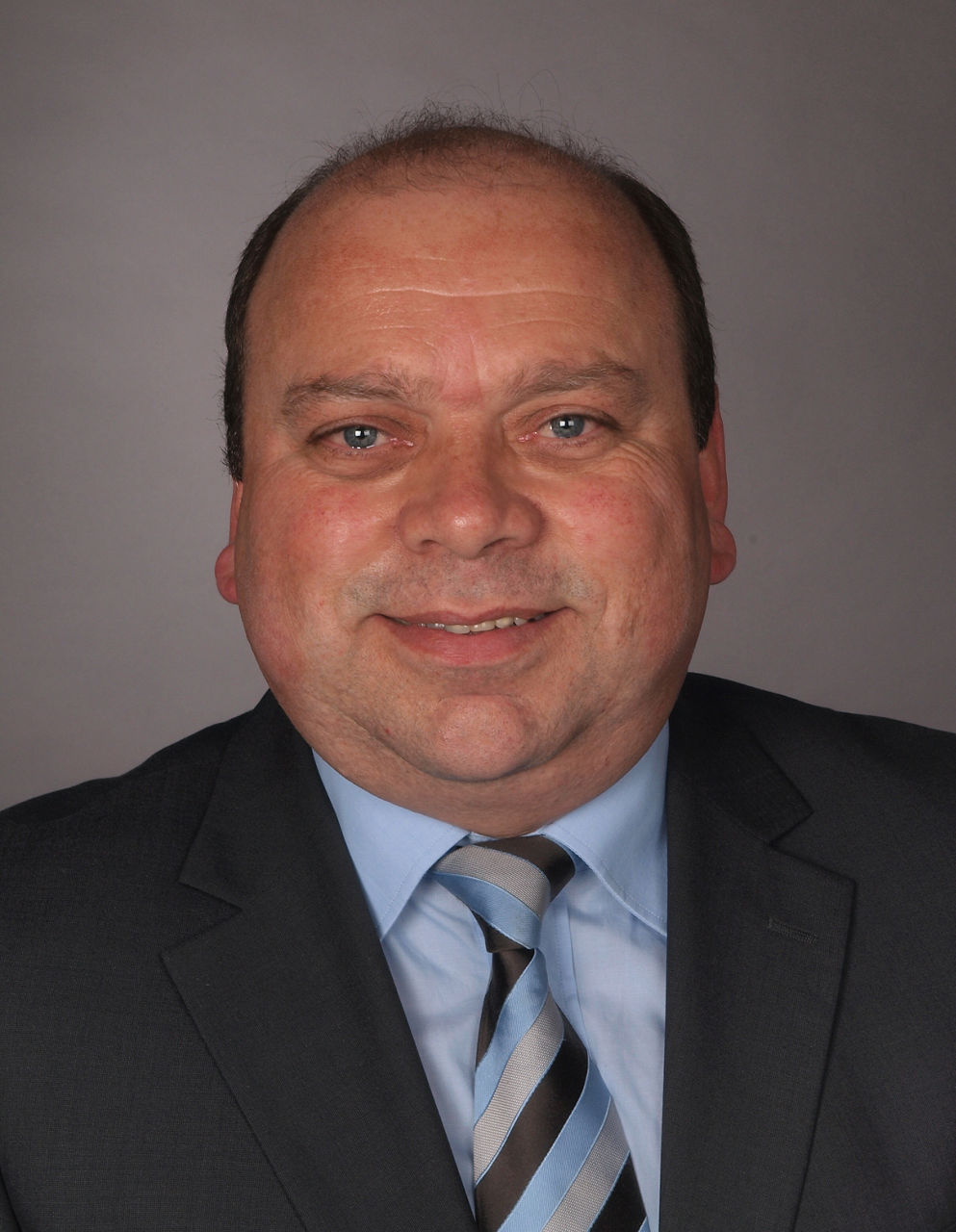 Mitarbeiter der Bank im Anzug mit Krawatte lächelt in die Kamera.