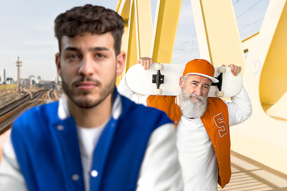 Ein junger Mann im Vordergrund, im Hintergrund ein älterer Mann, der ein Skateboard trägt