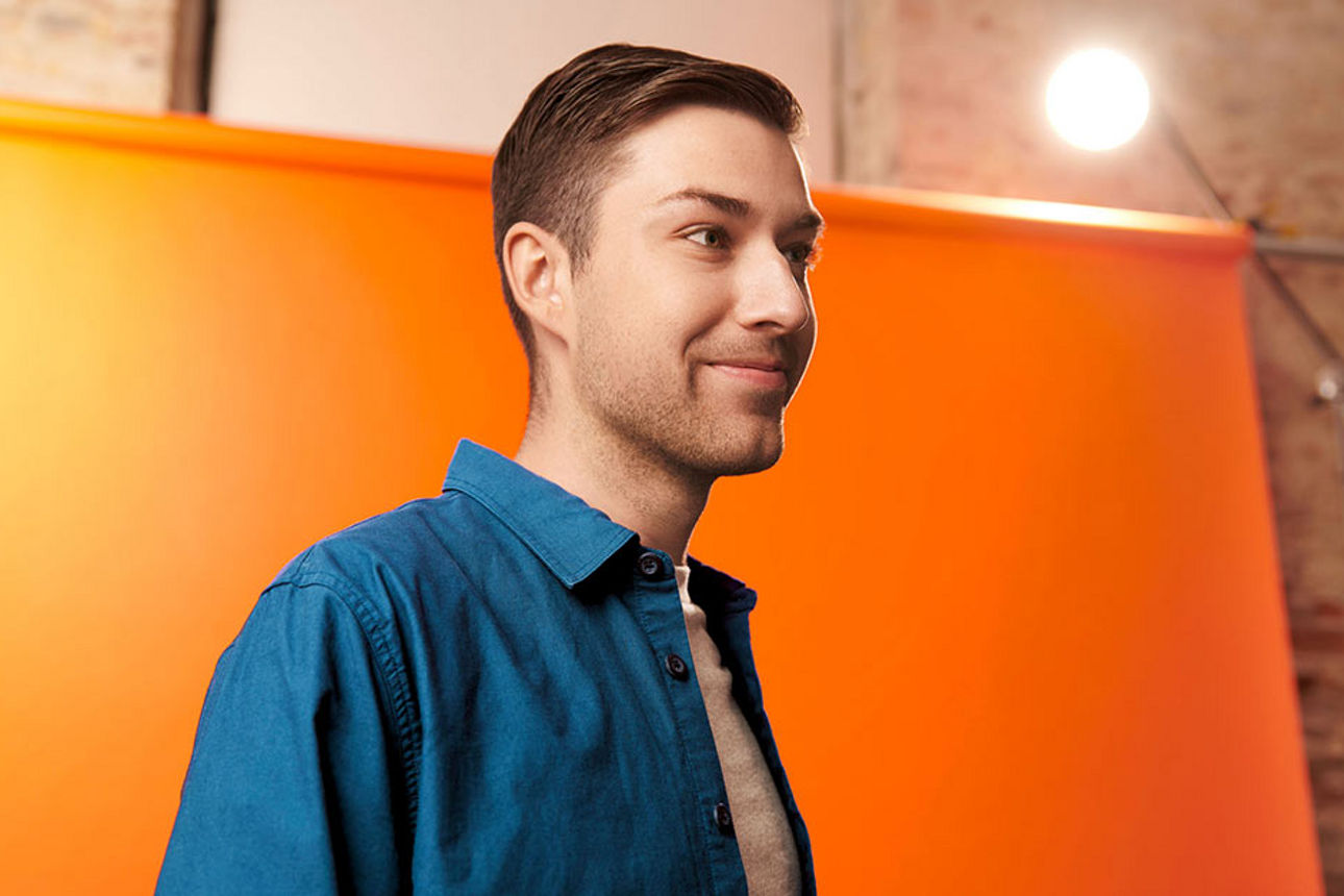 Ein Mann vor einer orangefarbenen Leinwand