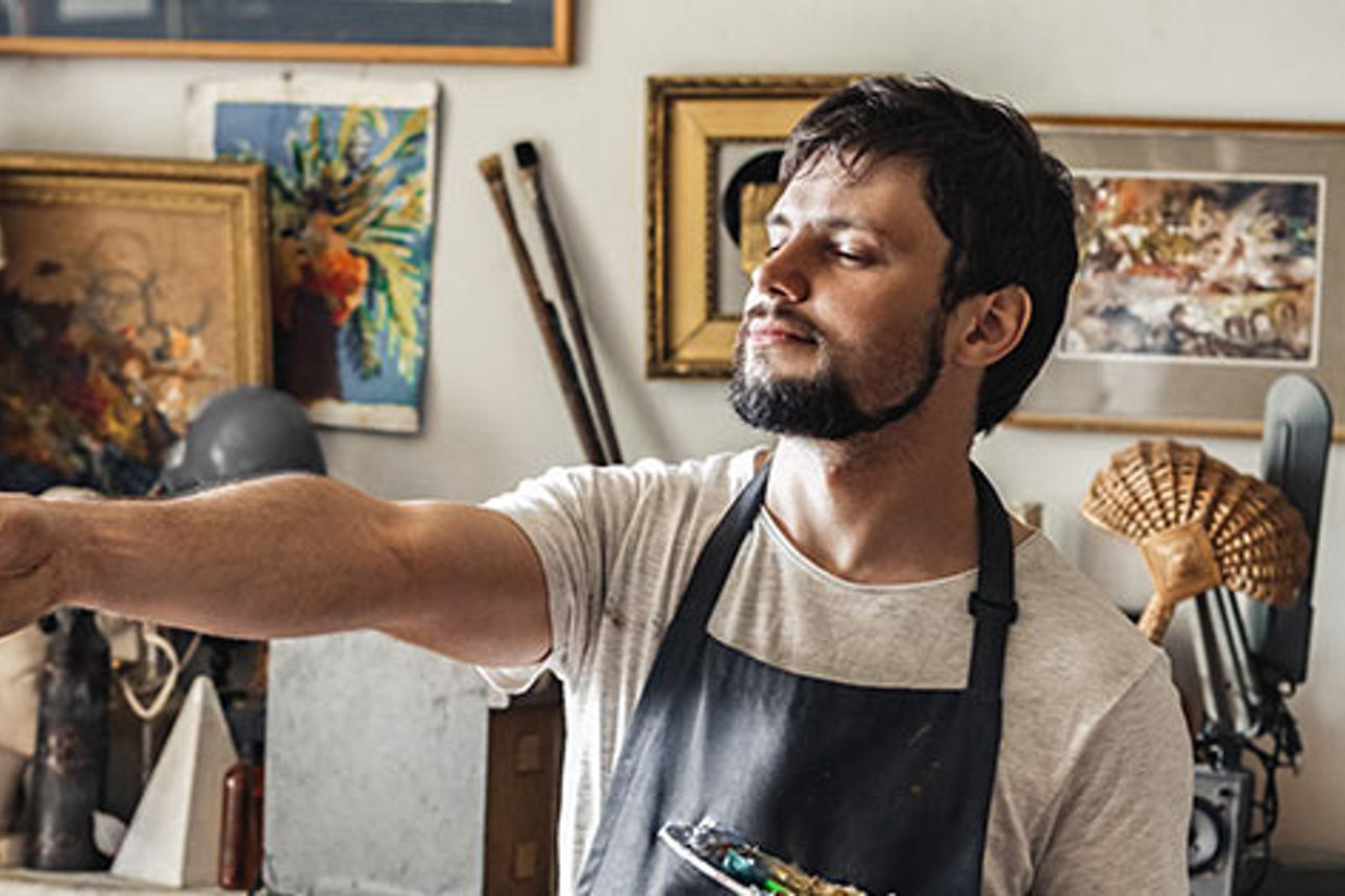 Mann mit Pinsel in der Hand steht in einem Atelier