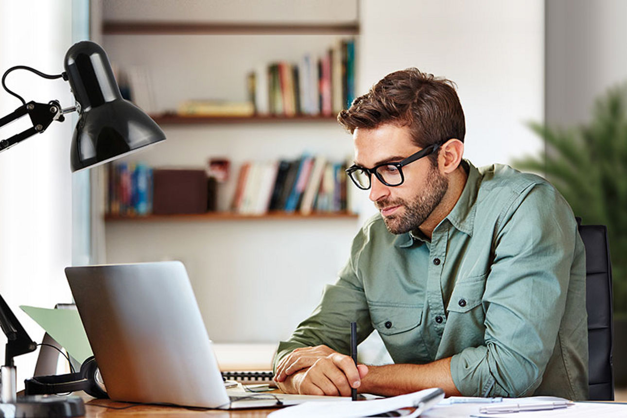 Mann sitzt mit Laptop an einem Schreibtisch