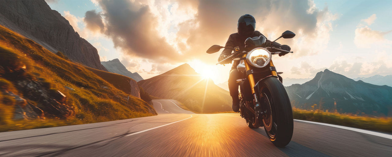 Ein Mann, der auf der Straße im Sonnenuntergang Motorrad fährt.