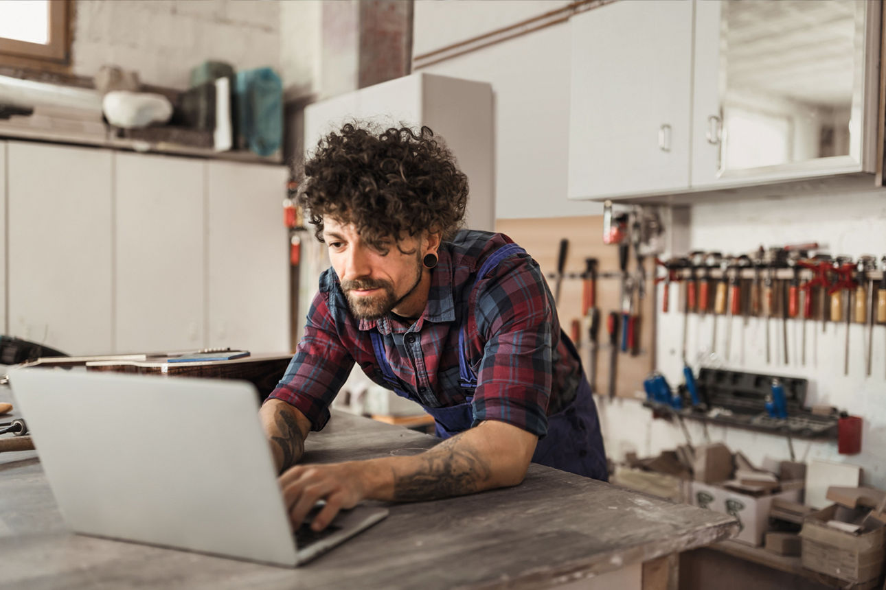 Person arbeitet an mehreren Bildschirmen mit Rechnungs- und Online-Banking-Anwendungen.