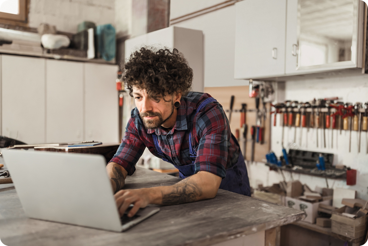 Person arbeitet an mehreren Bildschirmen mit Rechnungs- und Online-Banking-Anwendungen.