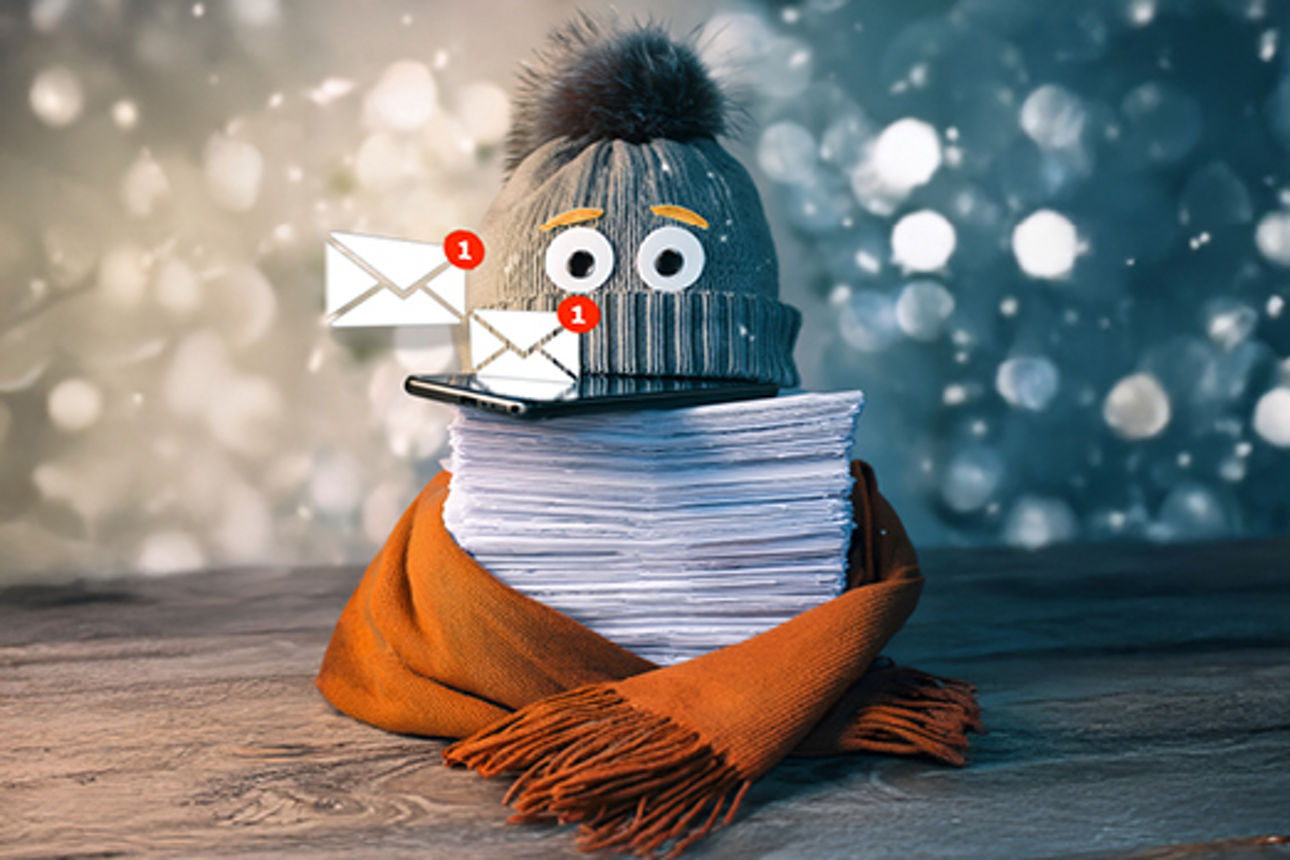 Papierstapel mit Schal und Mütze, dazwischen ein Smartphone über dem Briefumschläge schweben