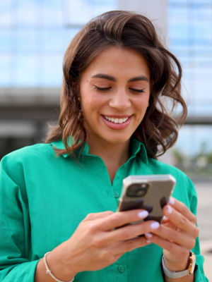 Frau schaut auf ihr Handy und lächelt dabei 