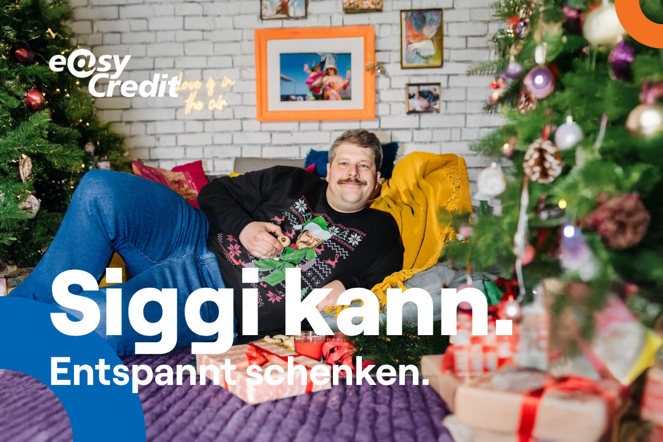 Ein Mann im Weihnachtspullover liegt entspannt auf seinem Sofa