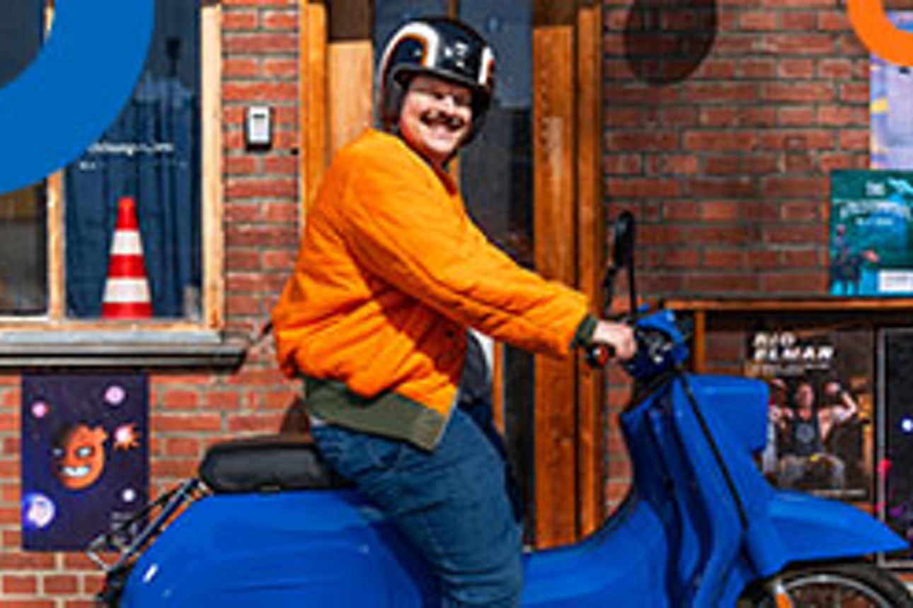 Mann sitzt lächelnd auf einem blauen Motorroller