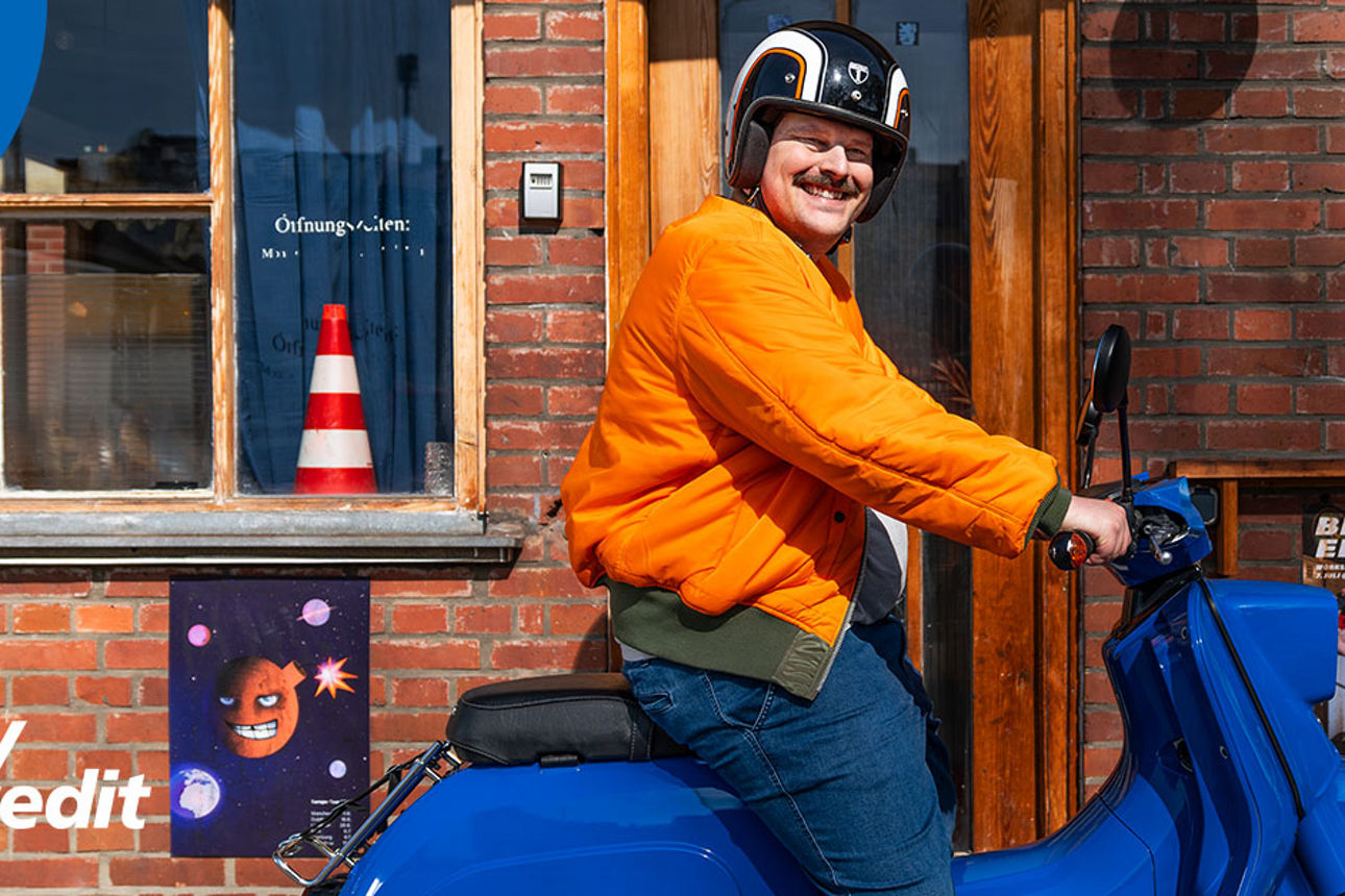 Mann mit Schnauzbart sitzt auf blauem Roller