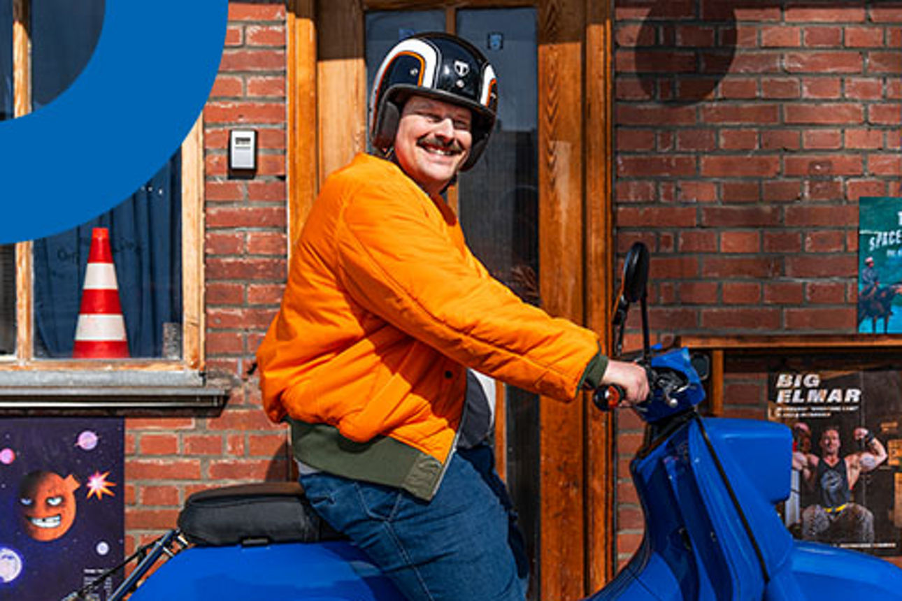 Mann mit organgener Jacke auf einem blauen Moped